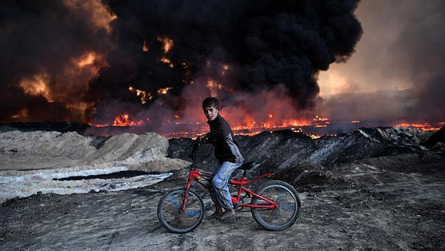 A boy passess an oil field set alight by ISIS fighters retreating from Mosul. Picture: Getty Images