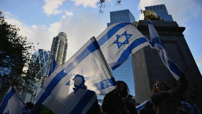 People wave the Flag of Israel during a memorial vigil for the Israeli civilians killed by Hamas during the October 7 attack.