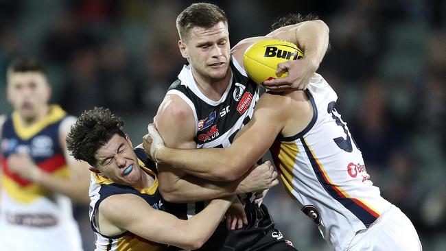 Port Adelaide’s Peter Ladhams is tackled by Adelaide’s Ned McHenry and Darcy Fogarty.