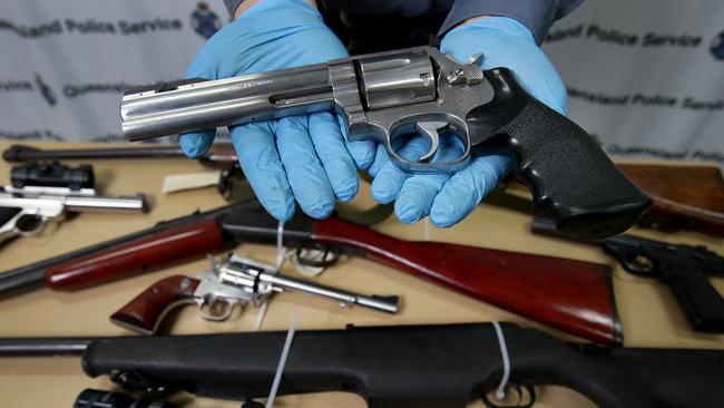 Detective Senior Constable Dale Lumma holds a .357 calibre pistol with some of the seized weapons from two operations targeting alleged bikie gang members in 2014. The five month operation yielded a seizure of more than $3.5m in vehicles, property, weapons, drugs and cash around the region and in Sydney.