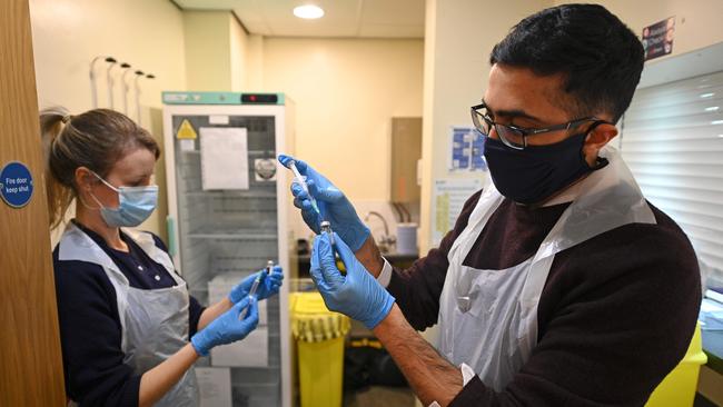 Pharmacist Naeem Khazee, right, and nurse Jocie Walsh dilute vials of Pfizer/BioNTech vaccine before doses are drawn to be administered at a vaccination centre set up at Thornton Little Theatre managed by Wyre Council in Thornton-Cleveleys, northwest England, on Friday. Picture: AFP