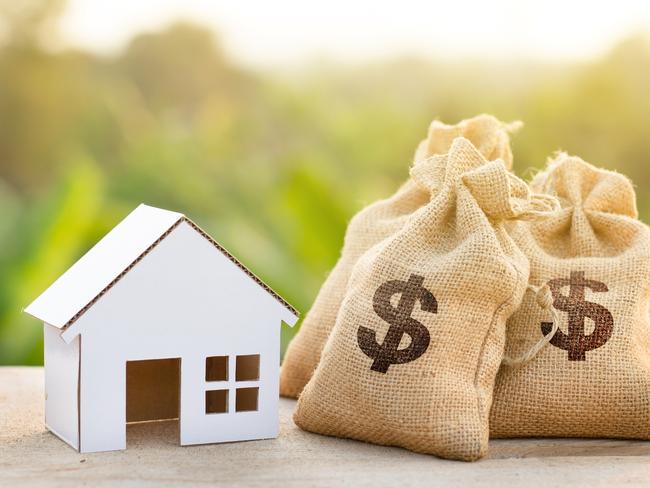 Loan and House concept. Money bags put near house on woodle desk at sunset and green nature background