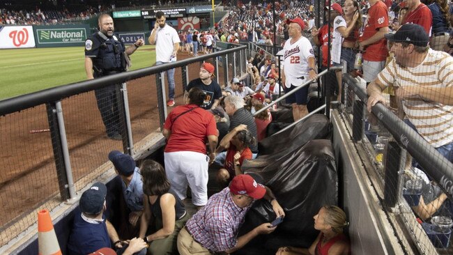 Fans take cover inside the dugout after gunfire was heard.