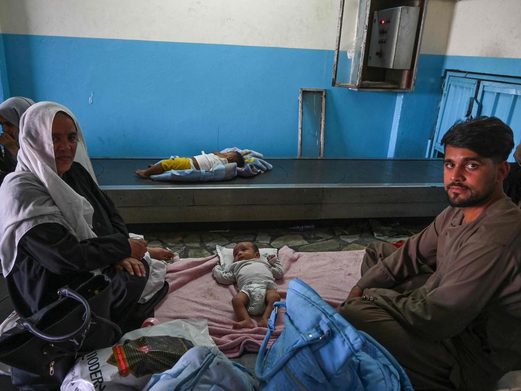 An Afghan family is seen caring for their babies on a luggage conveyor belt at Kabul Airport. Picture: Wakil Kohsar/AFP