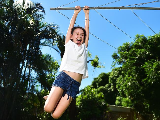 Leukaemia survivor Hannah Larsen, 11, swings from the Hills Hoist clothes line at her Hermit Park home. Picture: Shae Beplate.