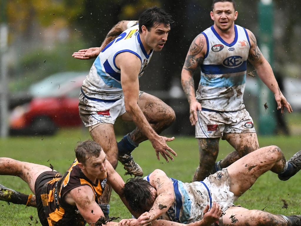 Players from Kilmore and Heidelberg West send mud flying as they vie for the ball. Pictures: Nathan McNeill.