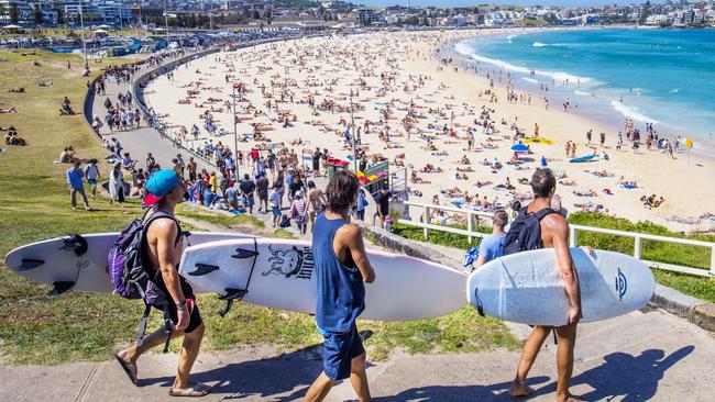 Three surfers heading to the Bondi Beach Bondi beach with their surf boards on a sunny day.Escape 28 April 2024Why I Travel - Carla OatesPhoto: iStock