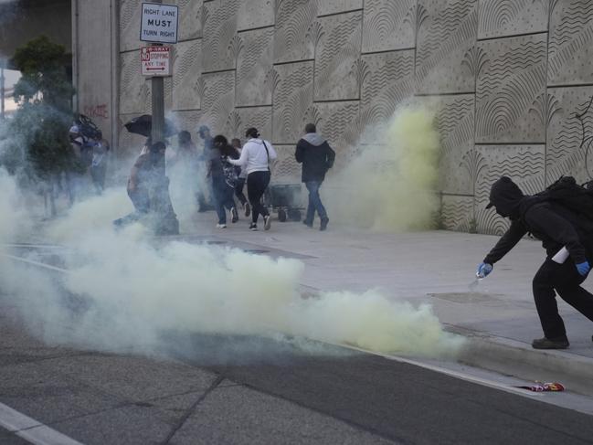 A protester pours water over a tear gas canister during a protest after federal immigration authorities conducted an operation. Picture: AP