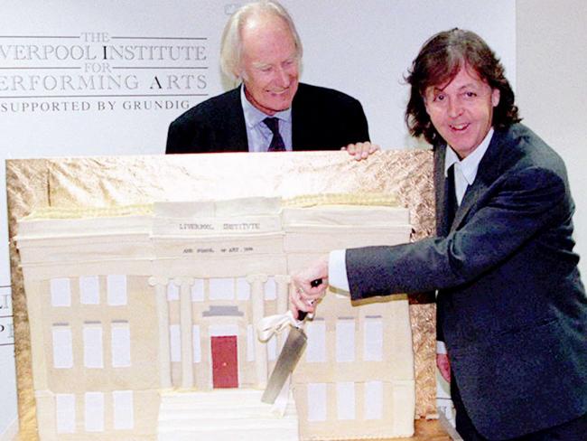 Paul McCartney and record producer George Martin pose with a cake in the form of the Liverpool Institute for Performing Arts during its opening ceremony.