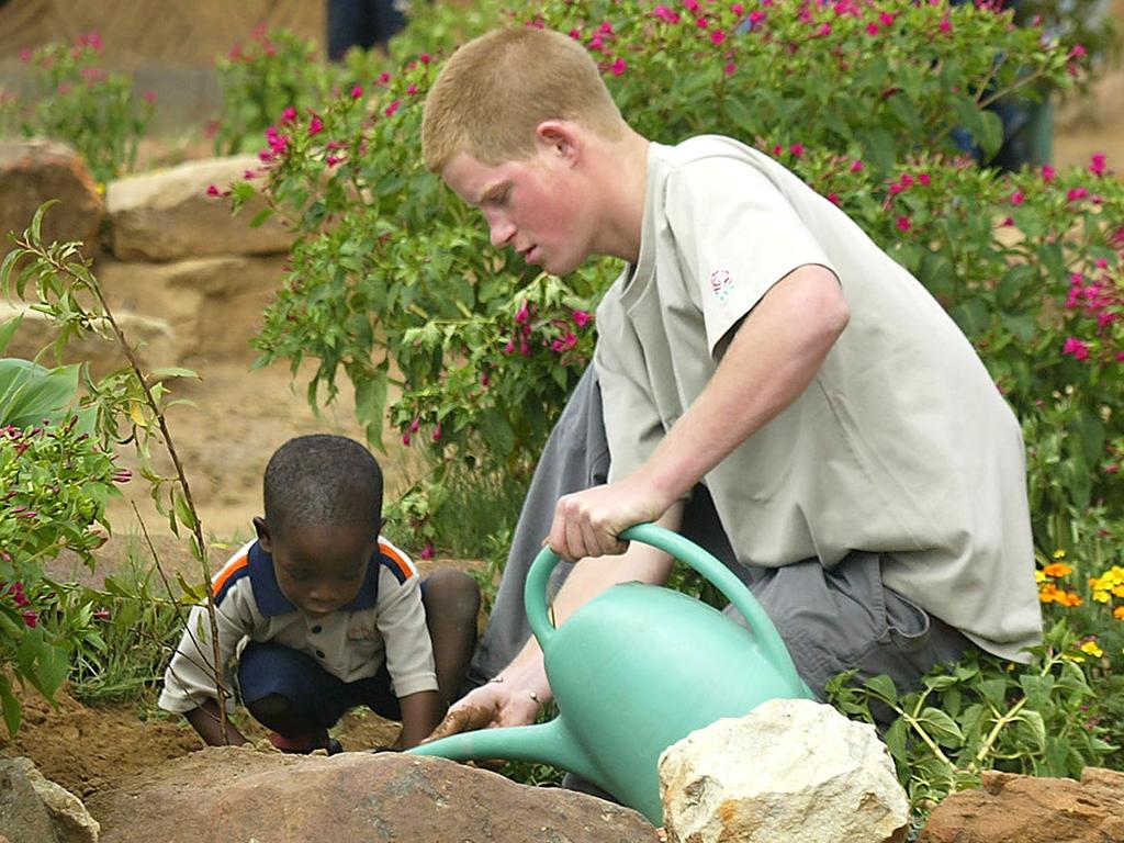 Prince Harry plants a peach tree with 4-year-old Mutsu Potsane at the Mants’ase Children’s Home on March 2, 2003 in South Africa. Picture: AAP