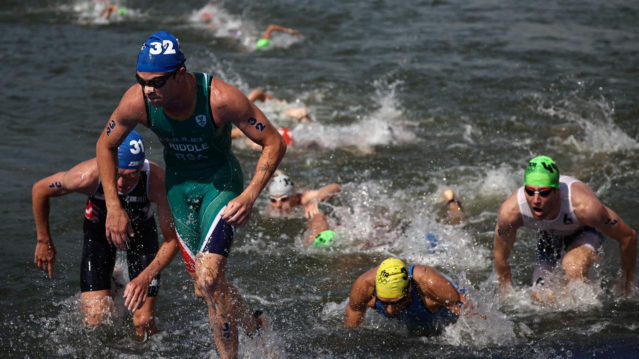 South Africa’s Jamie Riddle and other triathletes are seen exiting the water after their swim leg. Picture: Anne-Christine Poujoulat/AFP