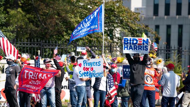 A single Biden, Harris, supporter holds a sign as Donald Trump supportersrally outside Walter Reed Medical Center in Bethesda, Maryland. Picture: AFP.