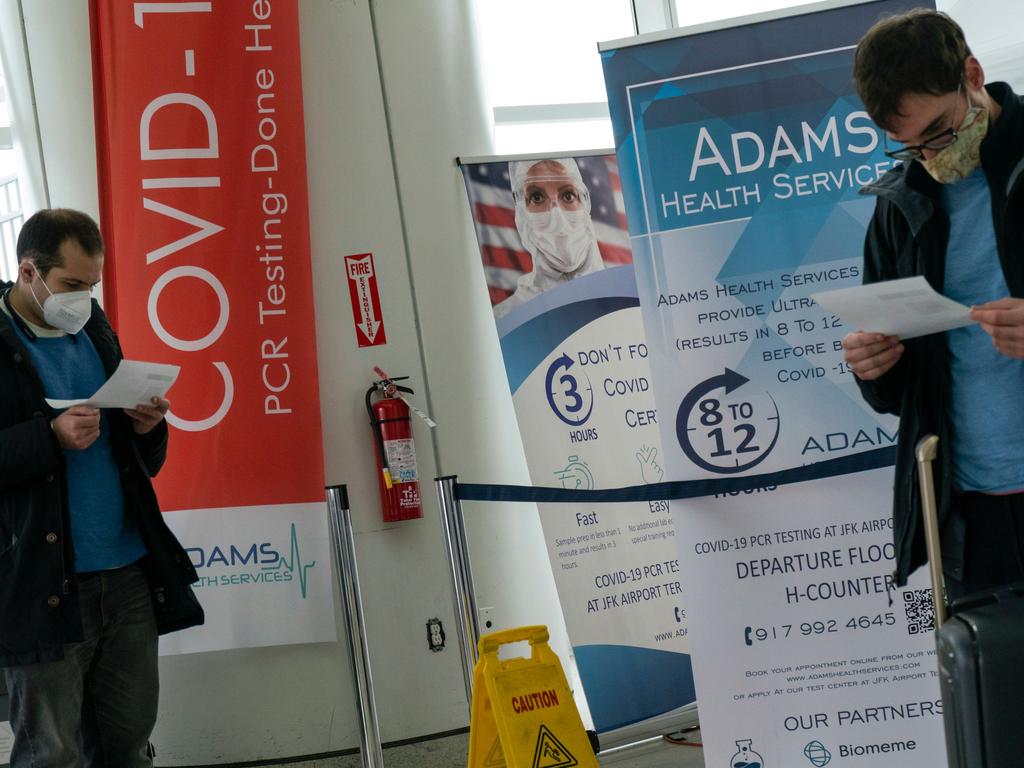 Travellers look at COVID-19 results after being tested inside JFK airport in New York. US authorities announced that passengers arriving on flights from the UK will need to test negative for coronavirus. Picture: AFP