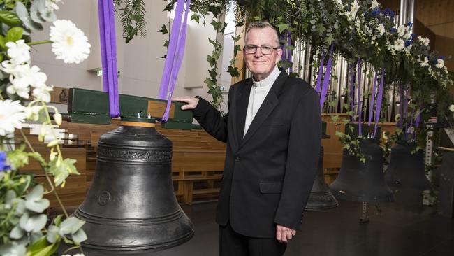 Fr Peter Williams with one of the eight bells ahead of its blessing in September. Picture: Dylan Robinson