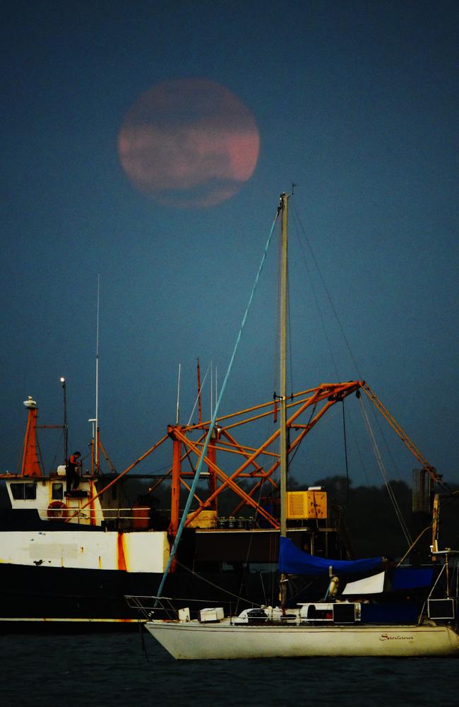 The Supermoon pokes through the thick cloud from a Darwin storm at Stokes Hill Wharf. Picture: News Corp Australia