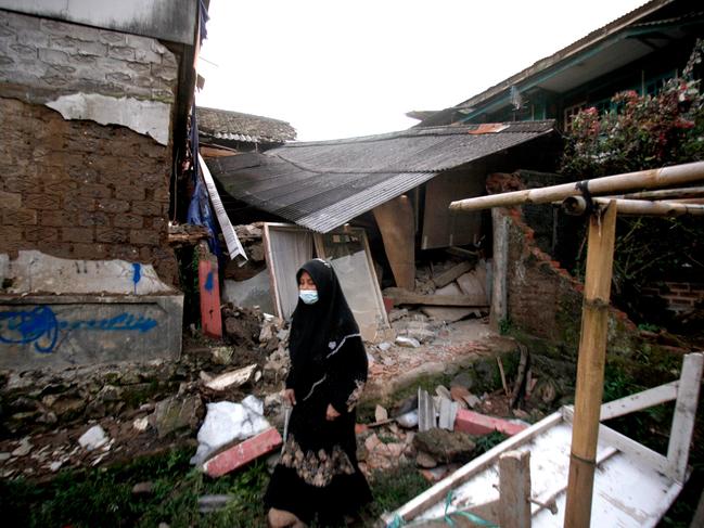 A woman walks past a damaged house following an earthquake in Cianjur on November 21, 2022. Picture: AFP.