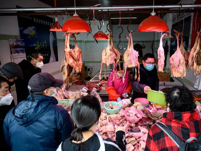 People wearing protective face masks shop at a chicken stall at a wet market in Shanghai. Picture: Noel Celis, AFP