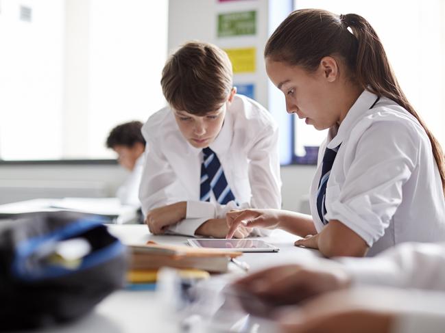 Two High School Students Wearing Uniform Working Together At Desk Using Digital Tablet Picture: Istock