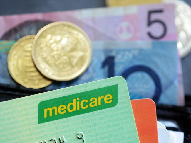 Bank notes and coins are seen with a Medicare Card in Brisbane, Wednesday, May 1, 2013. Prime Minister Julia Gillard today announced a levy to fund the National Disability Insurance Scheme. (AAP Image/Dave Hunt) NO ARCHIVING