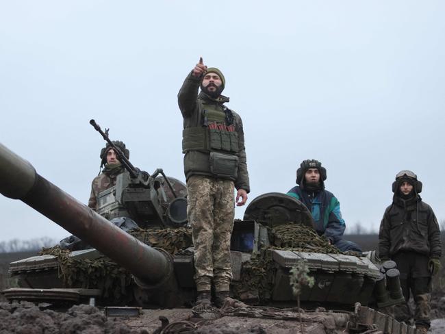 TOPSHOT - Ukrainian tankers stand atop their tank in a field near an undisclosed frontline position in eastern Ukraine on November 28, 2022, amid the Russian invasion of Ukraine. (Photo by Yevhen TITOV / AFP)