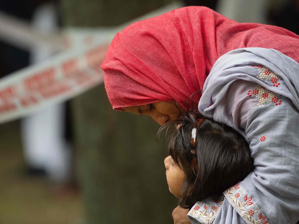 A Muslim woman holds her child as they stand across the road from the Dean Street mosque when worshippers were gunned down in Christchurch. Picture: AFP