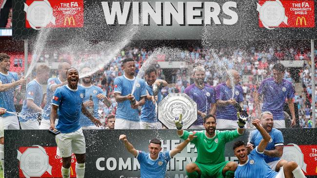 Manchester City players celebrate with the trophy.