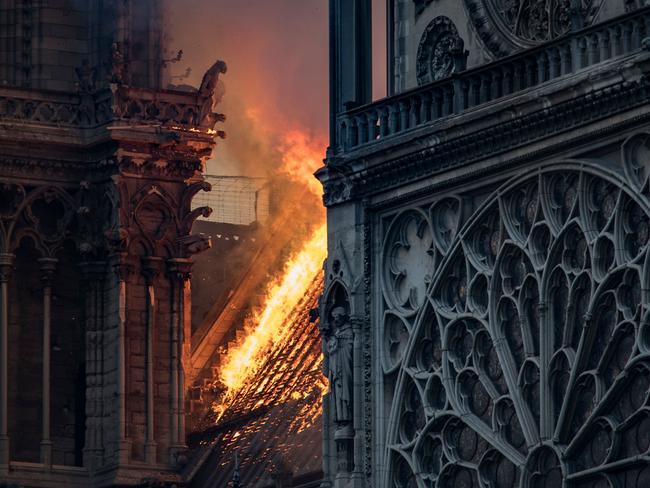 Flames and smoke are seen billowing from the roof at Notre-Dame Cathedral in Paris on April 15, 2019. - A huge fire swept through the roof of the famed Notre-Dame Cathedral in central Paris on April 15, 2019, sending flames and huge clouds of grey smoke billowing into the sky. The flames and smoke plumed from the spire and roof of the gothic cathedral, visited by millions of people a year. A spokesman for the cathedral told AFP that the wooden structure supporting the roof was being gutted by the blaze. (Photo by THOMAS SAMSON / AFP)