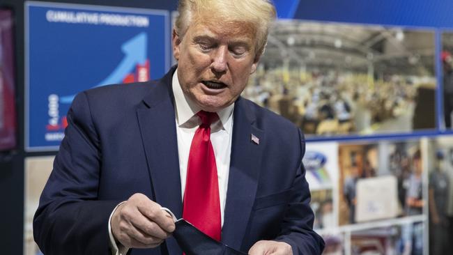 Donald Trump holds a protective face mask while touring a Ford factory in Michigan that has been converted to making personal protection and medical equipment. Picture: AP