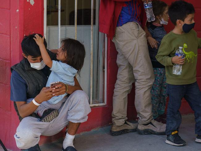 Migrants wait outside Gimnasio Kiki Romero, a gym which has been converted into a makeshift migrant shelter by the city of Juarez, after being expelled from the US to Mexico in Ciudad Juarez on April 6, 2021. (Photo by Paul Ratje / AFP)