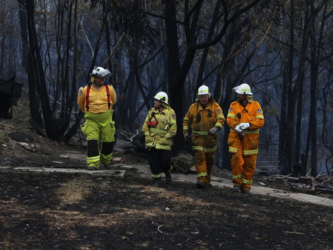 Firefighters walking through the blackened landscape after a fire ripped through the small town of Balmoral south west of Sydney for a second time on Saturday. Picture: Jane Dempster