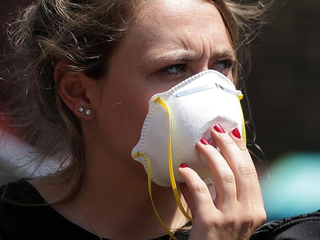 A woman wears a mask as she waits near a Grenfell Tower. Picture: Daniel Leal-Olivas