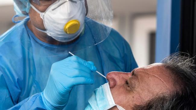 A health worker collects a nasal swab sample from a man.