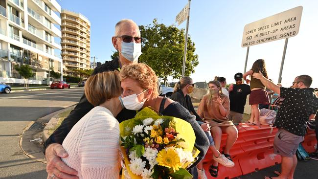 Belinda Vardy, gets hugs and flowers from her mum, Barbara Roberts, and father Max (on the NSW side) at Coolangatta on the Queensland-NSW border.