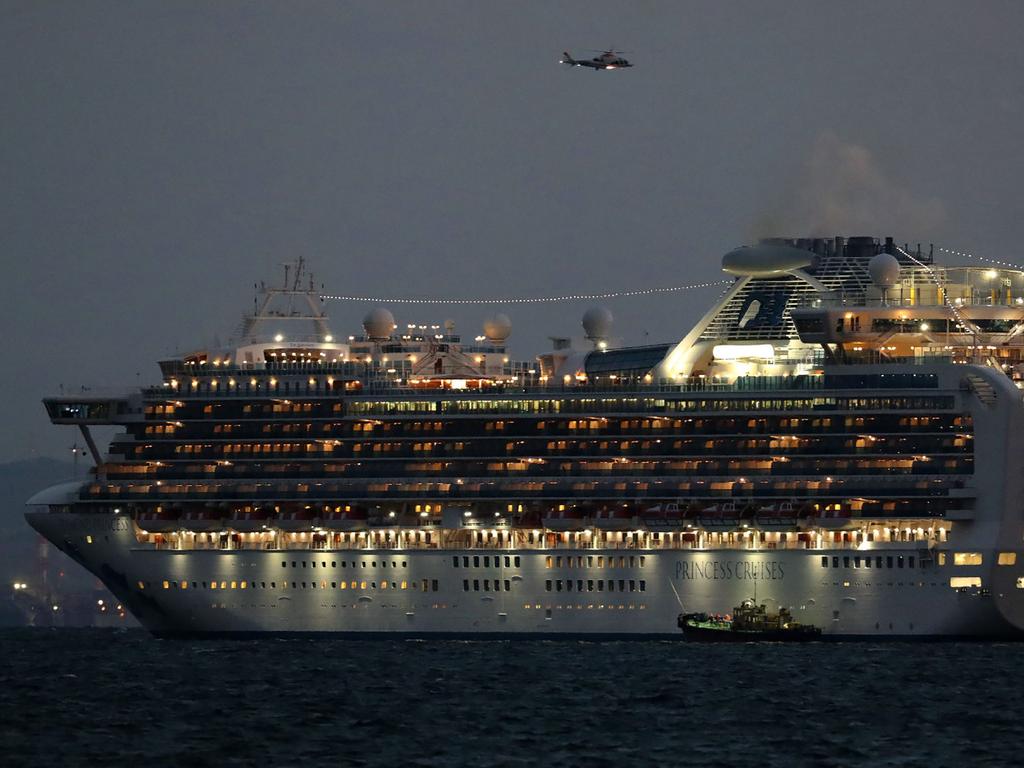 A small boat is pictured next to the Diamond Princess as it sits anchored in quarantine off the port of Yokohama. Picture: STR/JIJI PRESS/AFP