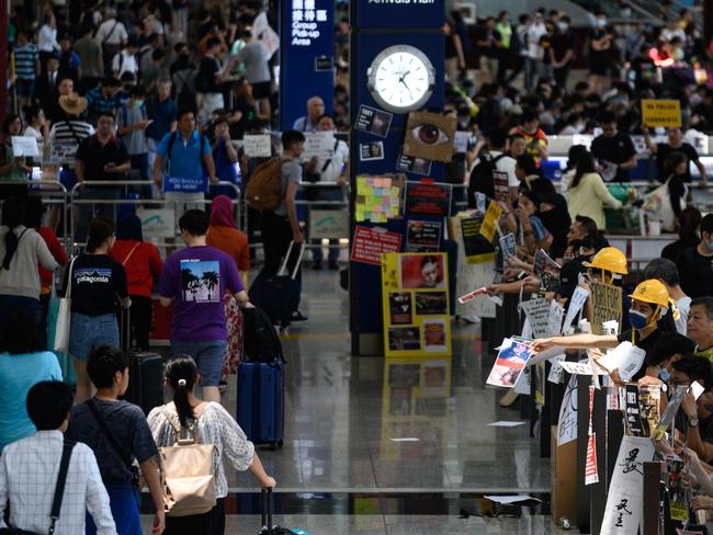 Pro-democracy protesters wear helmets as they deliver leaflets to arriving travellers. Picture: AFP