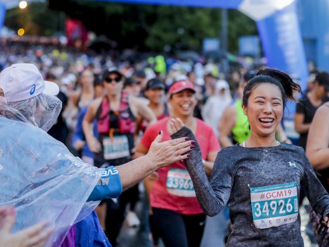 A volunteer high-fives competitors at the start of the very wet Southern Cross University 10 kilometre Fun Run. Pics Tim Marsden