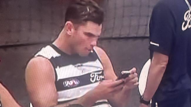 Tom Hawkins on the phone during the lightning break at the MCG on Monday.