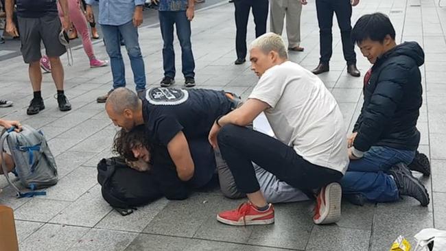 Barry Siecker is pinned down in Rundle Mall after a busker was attacked. Picture: Shaun Hollis.