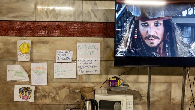 Children drawings are seen pasted on a wall as a movie plays on a television for people sheltering in a metro station that has turned into a bomb shelter on March 18, 2022 in Kyiv, Ukraine. Picture: Chris McGrath/Getty Images