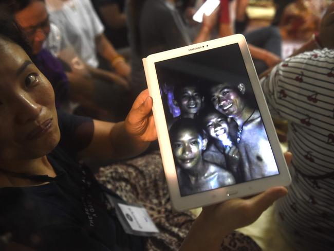 A family member shows a picture of four of the Wild Boars while they were still trapped in the Tham Luang cave. Against All Odds reveals a little bit of the personalities of each member of the team. Picture: AFP/Lillian Suwanrumpha