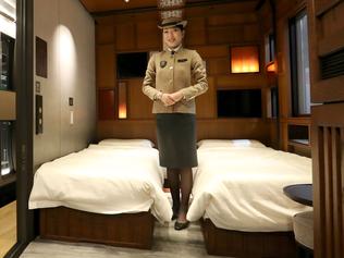 This picture taken on March 16, 2017 shows a crew member introducing a suite room of the Train Suite Shiki-Shima, operated by East Japan Railway, in Tokyo during a press preview. The luxury sleeper Shiki-Shima, which can accommodate up to 34 passengers, has 10 cars, including a lounge car, a dining car and two observatory cars. The train has only 17 cabins, all suites, and the most expensive room, known as Shiki-Shima Suite, is priced at 950,000 yen (8480 USD) per person when shared by two people.  / AFP PHOTO / JIJI PRESS / str / Japan OUT