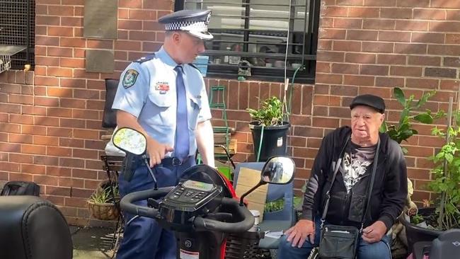 Police giving the scooter back to Mr Adams. Picture: Mitchell Van Homrigh