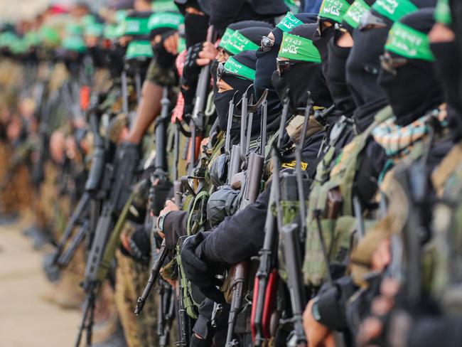 TOPSHOT - Hamas fighters secure an area before handing over three Israeli hostages to a Red Cross team in Deir el-Balah, central Gaza, on February 8, 2025. Hamas militants handed over three Israeli hostages on February 8, as part of the fifth exchange under a fragile Gaza ceasefire, with 183 prisoners held by Israel due to be released later in the day. (Photo by Eyad BABA / AFP)