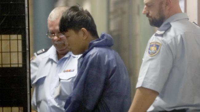 A man believed to be Shuo Dong is led to a prison van at Burwood Local Court, Sydney in 2018. Picture: AAP