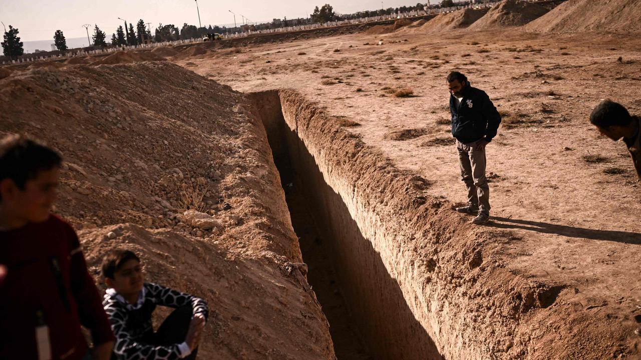 People stand next to a trench believed to be used as a mass grave on the outskirts of Damascus. Picture: Aris Messinis/AFP