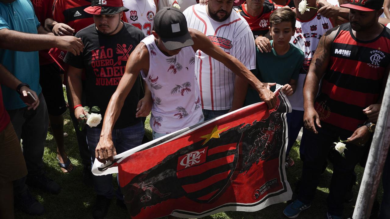 A fan holds a Flamengo flag as he and other fans pay a homage to the fire victims at the entrance Flamengo’s training complex in Rio de Janeiro.