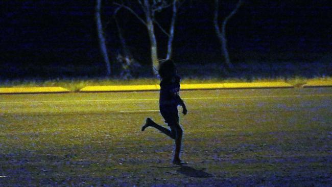 A young girl runs past a petrol station in Tennant Creek after dark. Children as young as seven roam the streets in Tennant Creek.