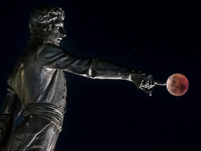 Blood Moon last night in Adelaide , with the Colonel Light Statue . Picture : Steven Genesin