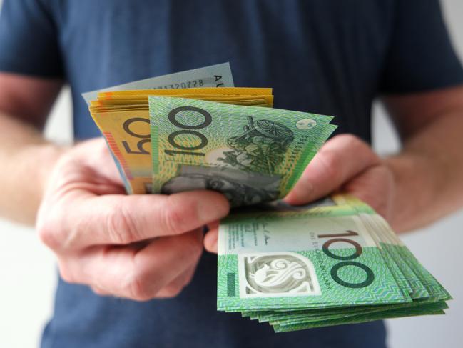 A man counting Australian dollar bills. A picture that describes buying, paying, handing out money, or showing money. Australian cash money generic