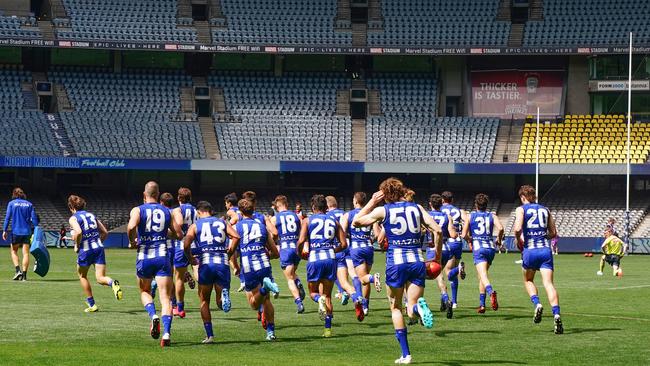 Kangaroos players run out into an empty Marvel Stadium on Sunday